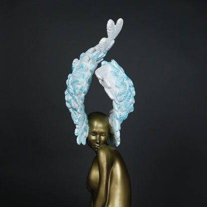 Gold-bodied woman sculpture with large white and blue feathered wings on a black base — luxury artistic décor piece.