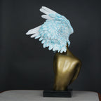 Gold-bodied woman sculpture with large white and blue feathered wings on a black base — luxury artistic décor piece.
