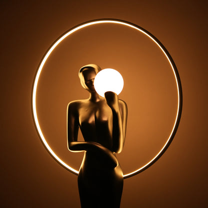 Tall matte-black lady sculpture floor lamp with glowing halo ring and warm globe light