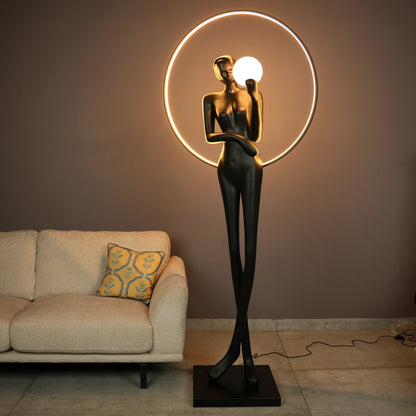 Tall matte-black lady sculpture floor lamp with glowing halo ring and warm globe light