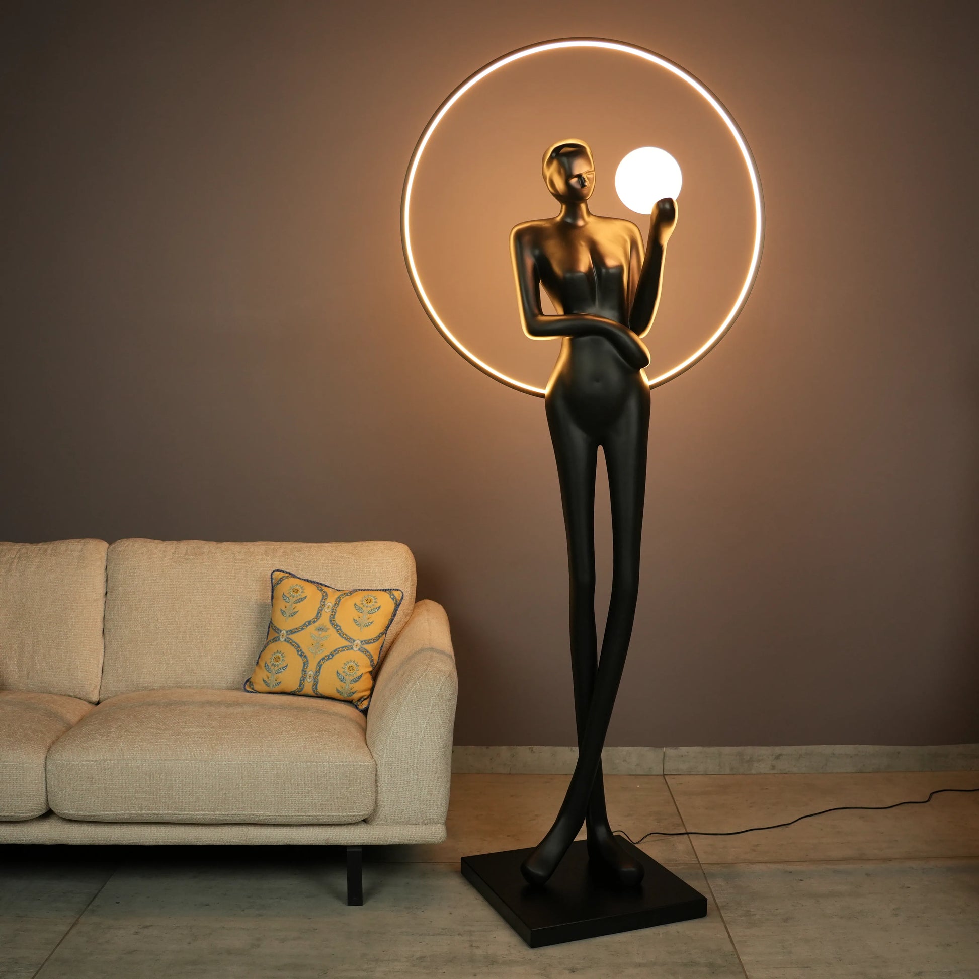 Tall matte-black lady sculpture floor lamp with glowing halo ring and warm globe light