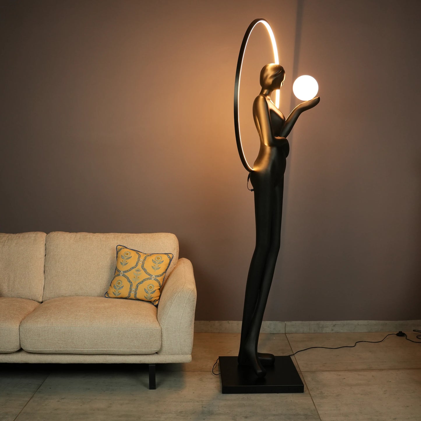 Tall matte-black lady sculpture floor lamp with glowing halo ring and warm globe light