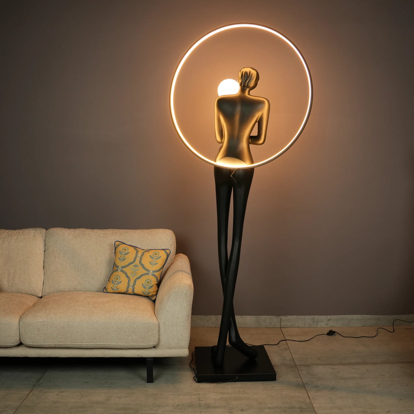 Tall matte-black lady sculpture floor lamp with glowing halo ring and warm globe light