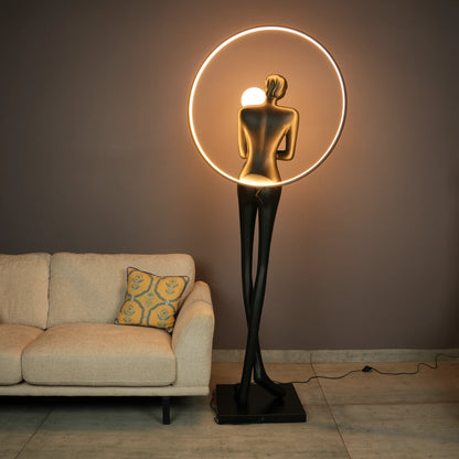 Tall matte-black lady sculpture floor lamp with glowing halo ring and warm globe light