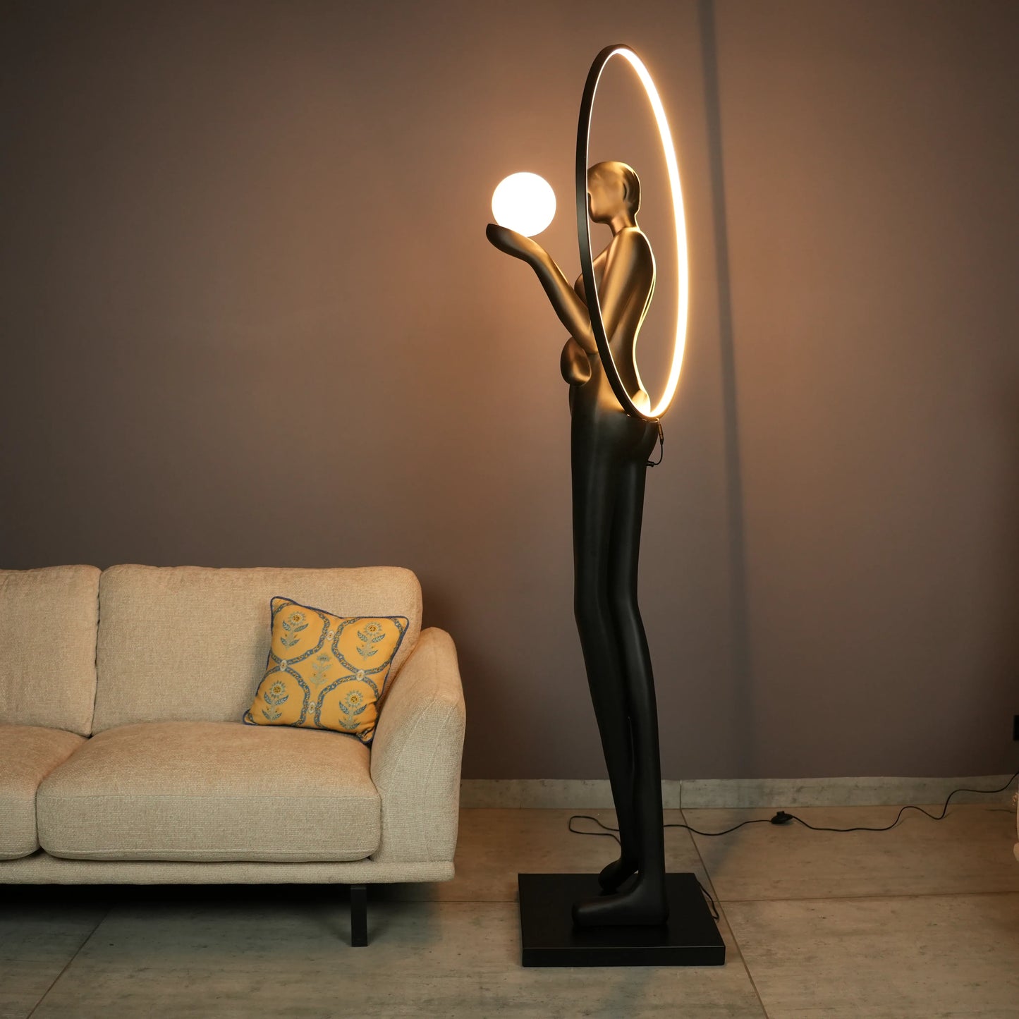 Tall matte-black lady sculpture floor lamp with glowing halo ring and warm globe light