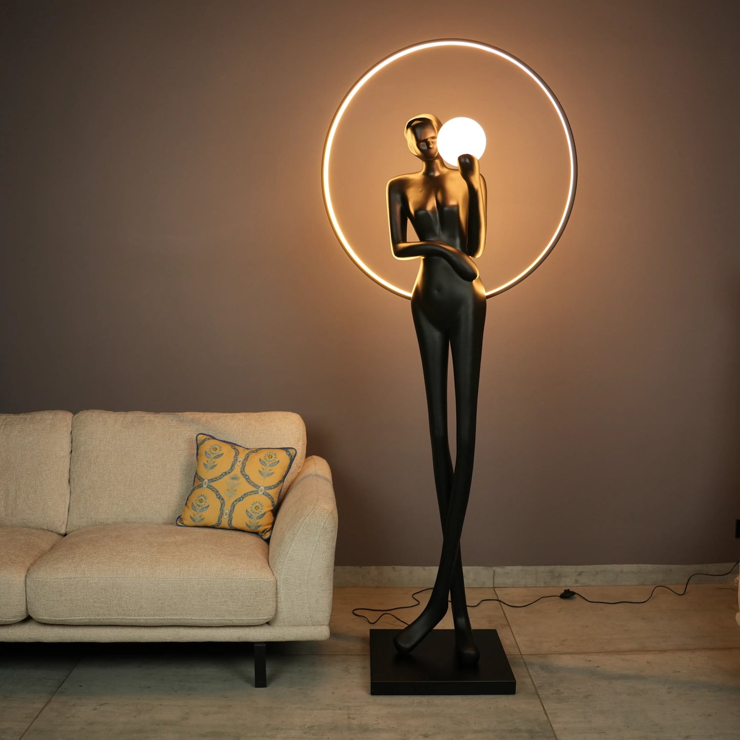 Tall matte-black lady sculpture floor lamp with glowing halo ring and warm globe light