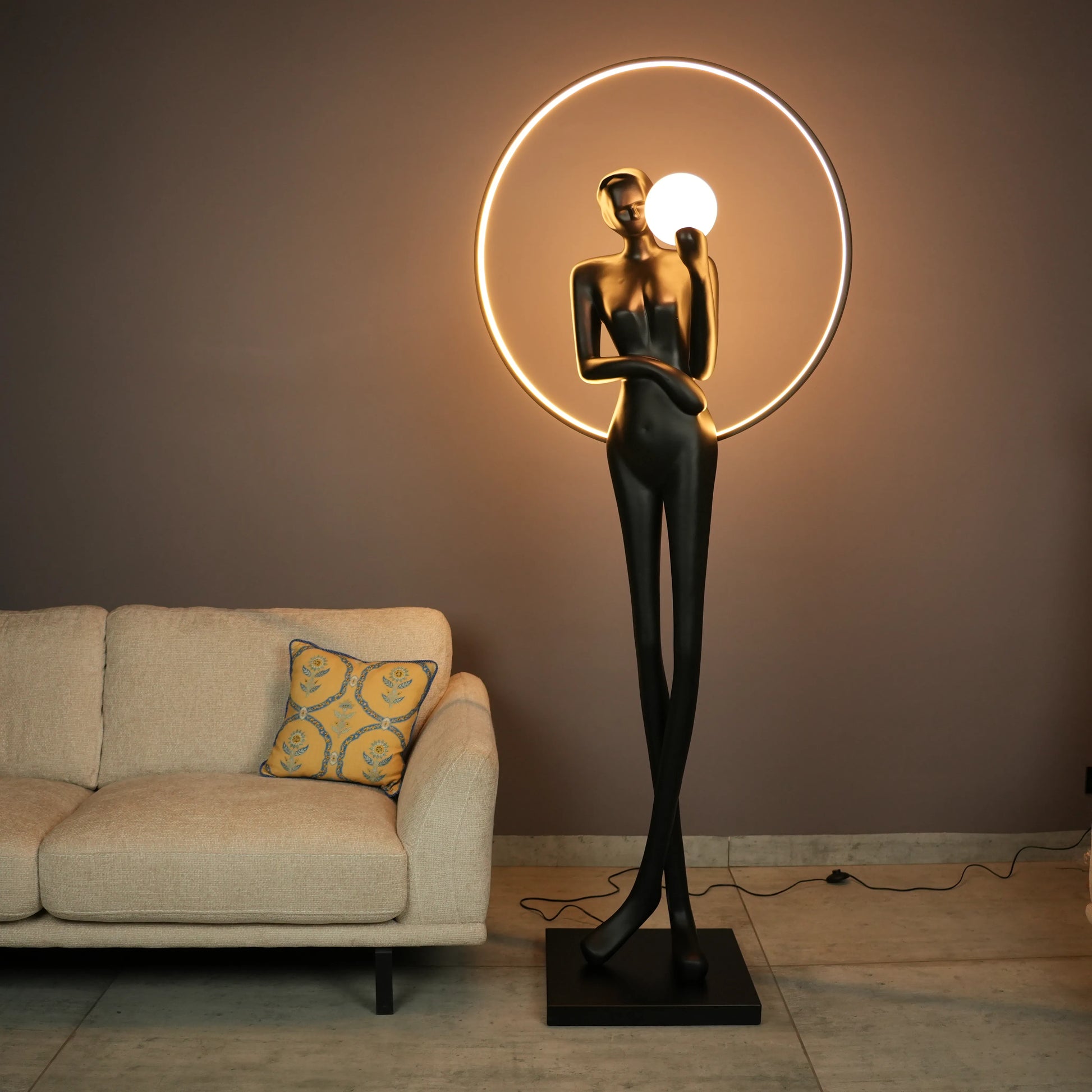 Tall matte-black lady sculpture floor lamp with glowing halo ring and warm globe light