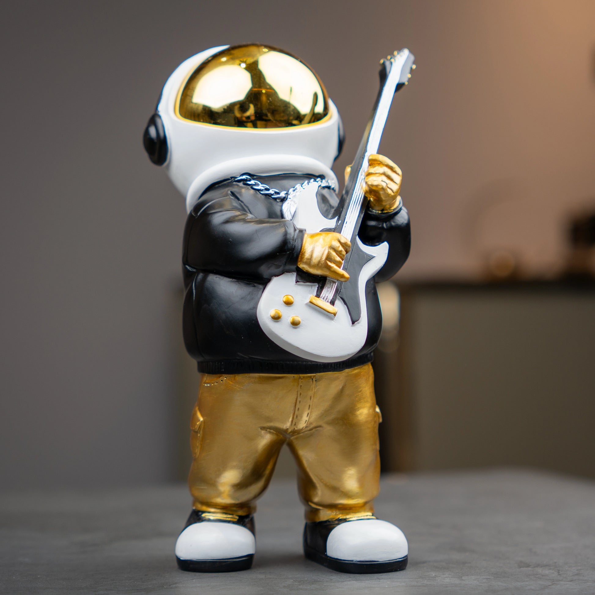 Small astronaut figurine playing guitar with gold helmet and metallic finish — Cosmic Rockstar Figurine by Ghar Art, handcrafted modern tabletop decor collectible.