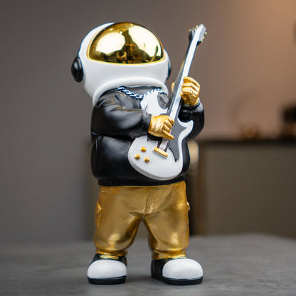 Small astronaut figurine playing guitar with gold helmet and metallic finish — Cosmic Rockstar Figurine by Ghar Art, handcrafted modern tabletop decor collectible.