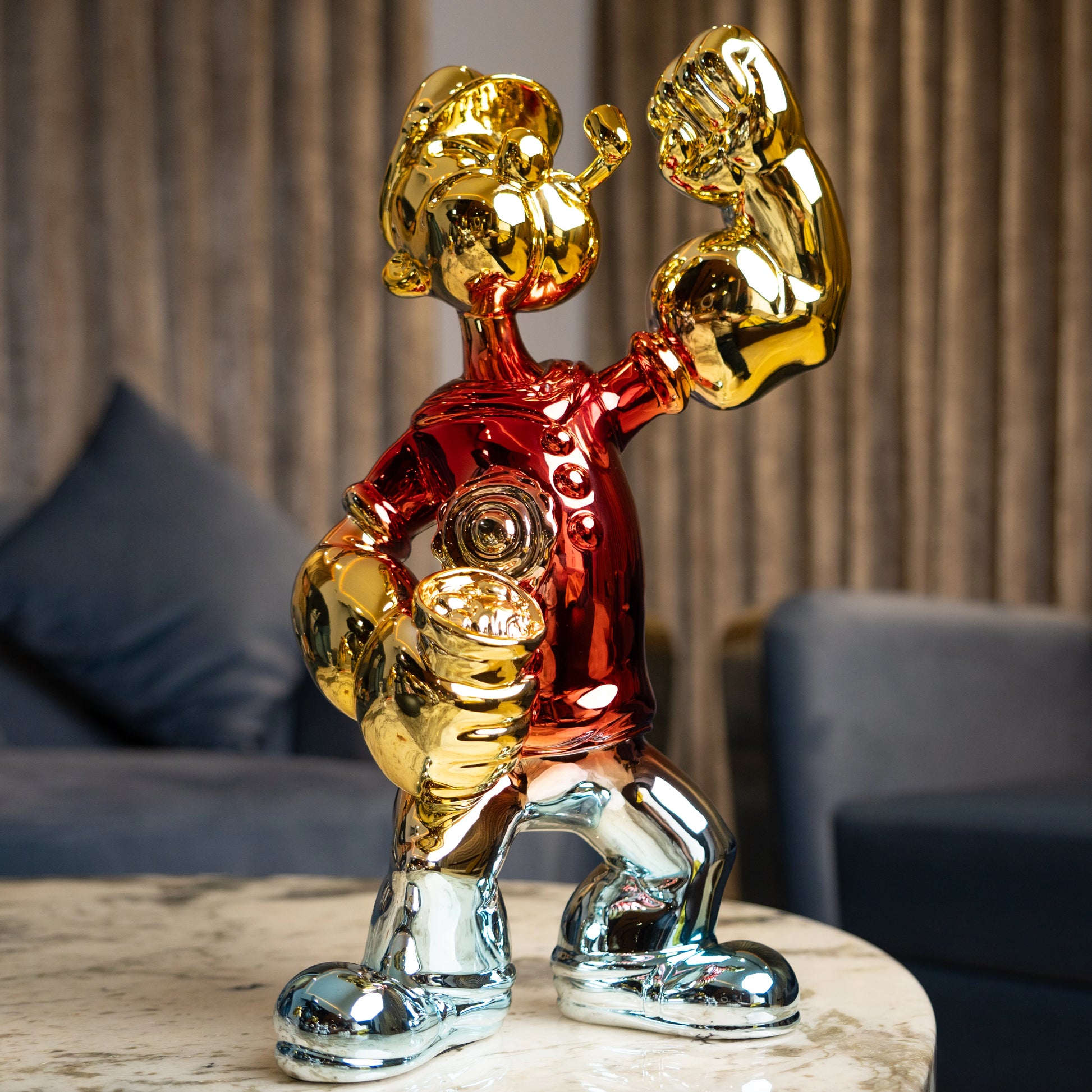Red, gold, and silver metallic resin figurine in a dynamic pose — luxury electroplated decorative sculpture by Ghar Art.