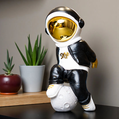Resin astronaut figurine with gold visor in streetwear, leaning on a moon sphere — Cosmic Voyager by Ghar Art.