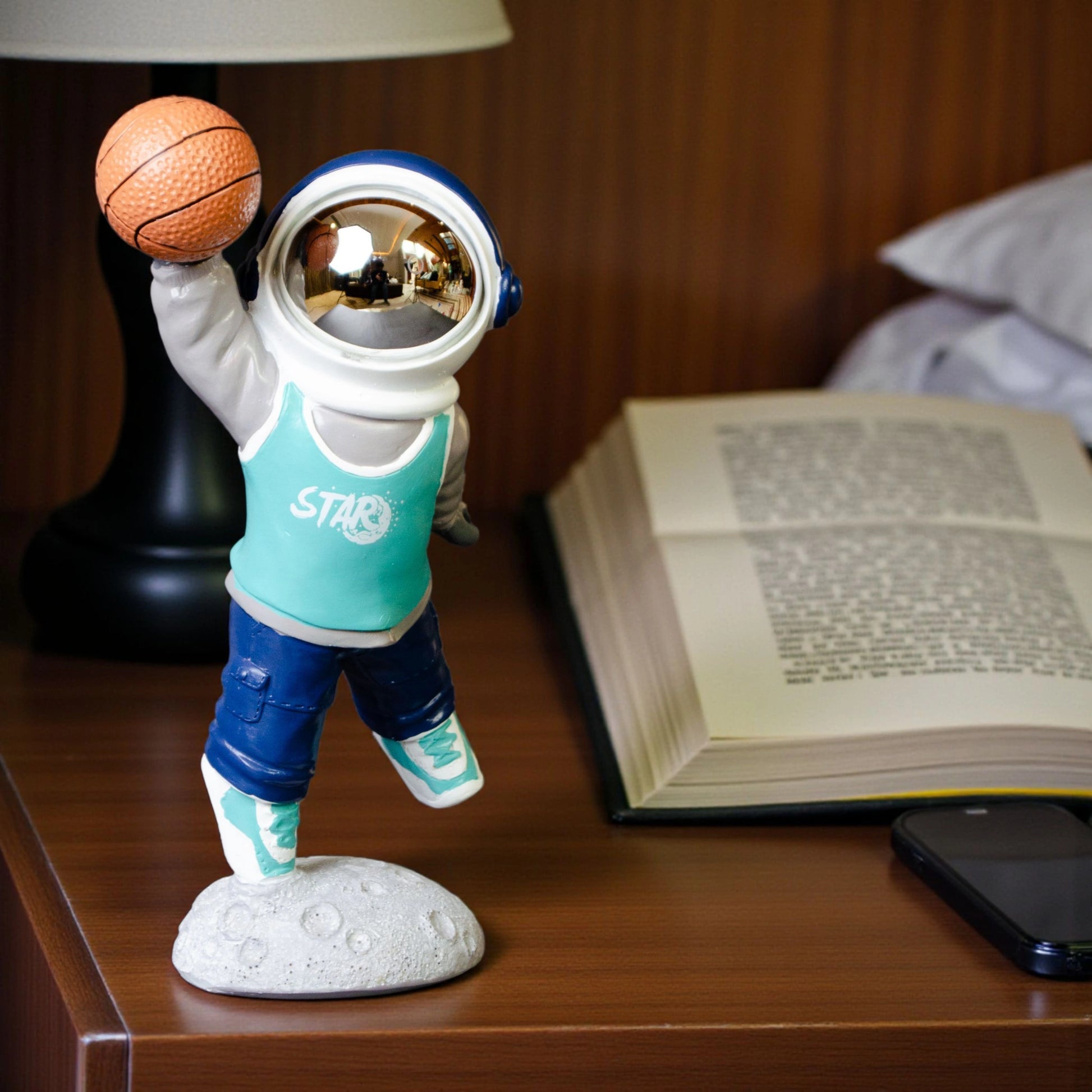 Astronaut figurine dribbling a basketball on a moon base with teal jersey and gold visor