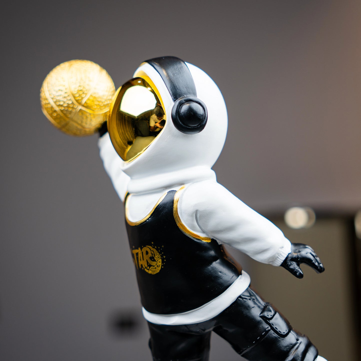 Astronaut figurine holding gold basketball, standing on moon-textured base — Cosmic Dunk Figurine by Ghar Art, handcrafted luxury modern tabletop decor collectible.