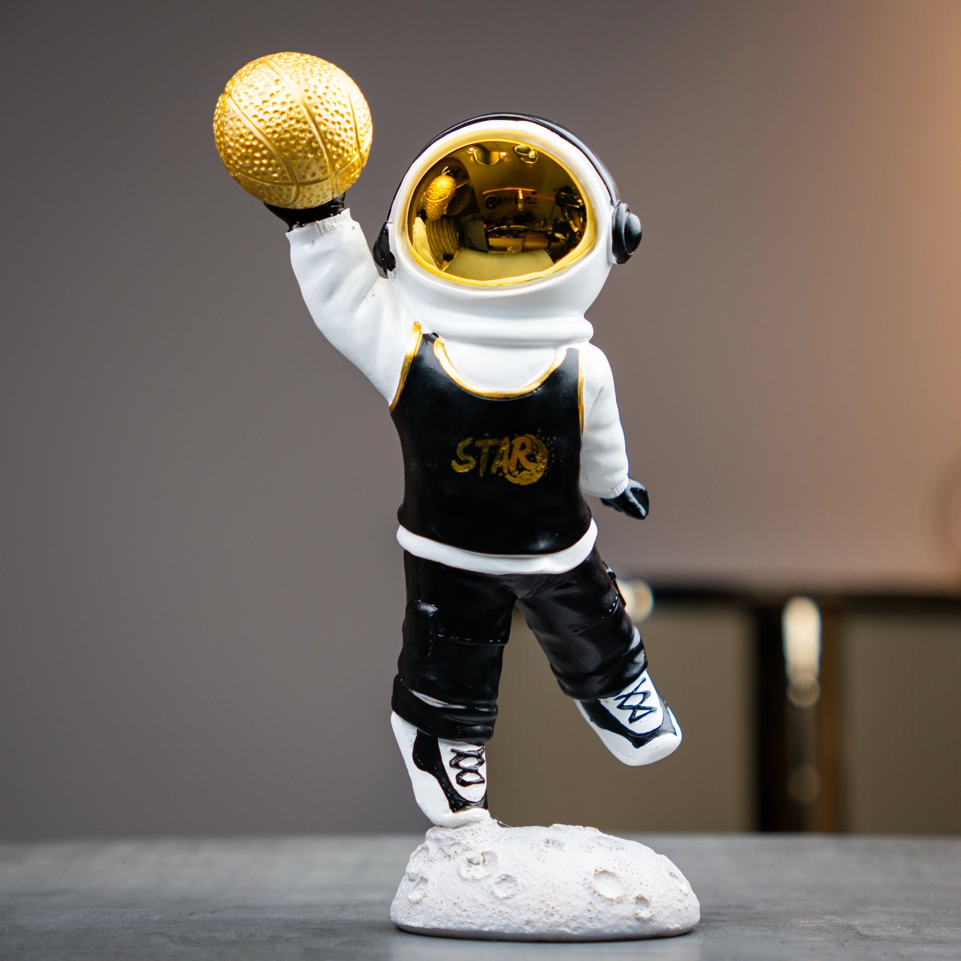Astronaut figurine holding gold basketball, standing on moon-textured base — Cosmic Dunk Figurine by Ghar Art, handcrafted luxury modern tabletop decor collectible.