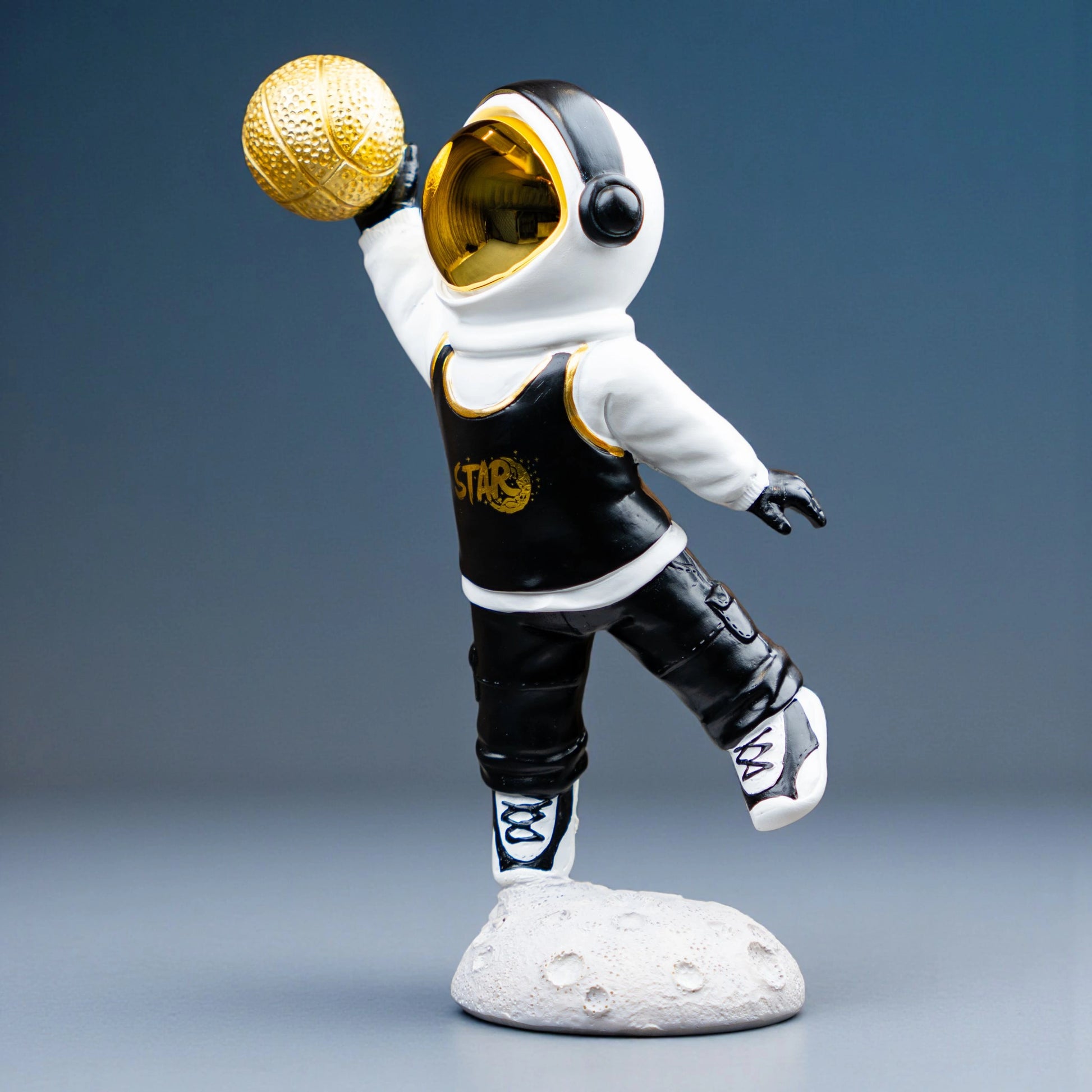 Astronaut figurine holding gold basketball, standing on moon-textured base — Cosmic Dunk Figurine by Ghar Art, handcrafted luxury modern tabletop decor collectible.