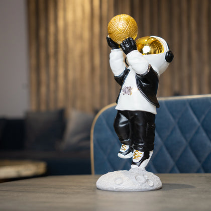 Astronaut figurine in black-and-white streetwear shooting a gold basketball on a moon base — Cosmic Shooter Figurine by Ghar Art.