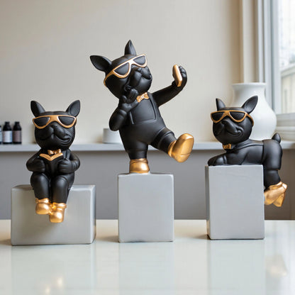 Black resin bulldog figurine trio with gold accents displayed on modern pedestal blocks