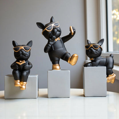 Black resin bulldog figurine trio with gold accents displayed on modern pedestal blocks