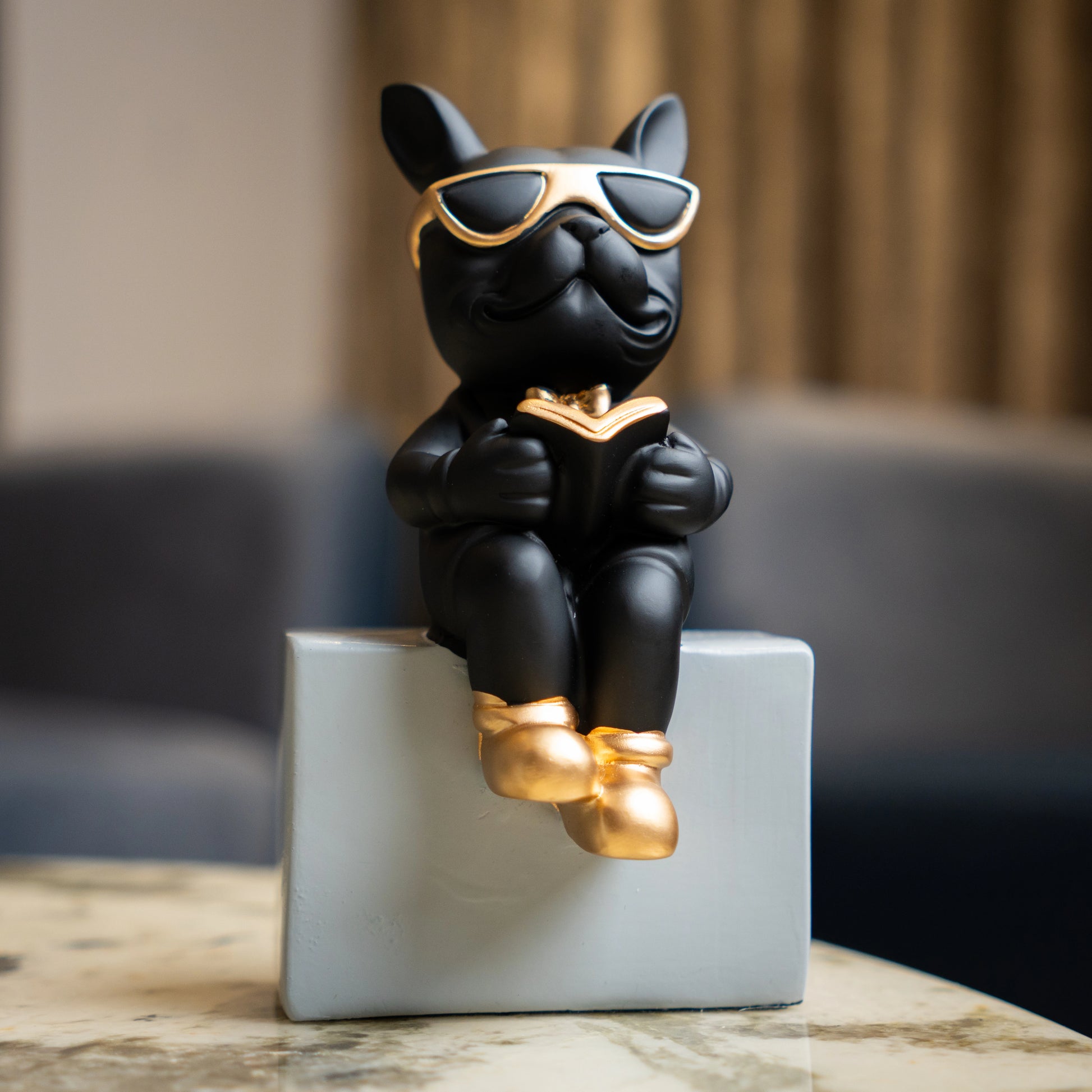 Black resin bulldog figurine trio with gold accents displayed on modern pedestal blocks