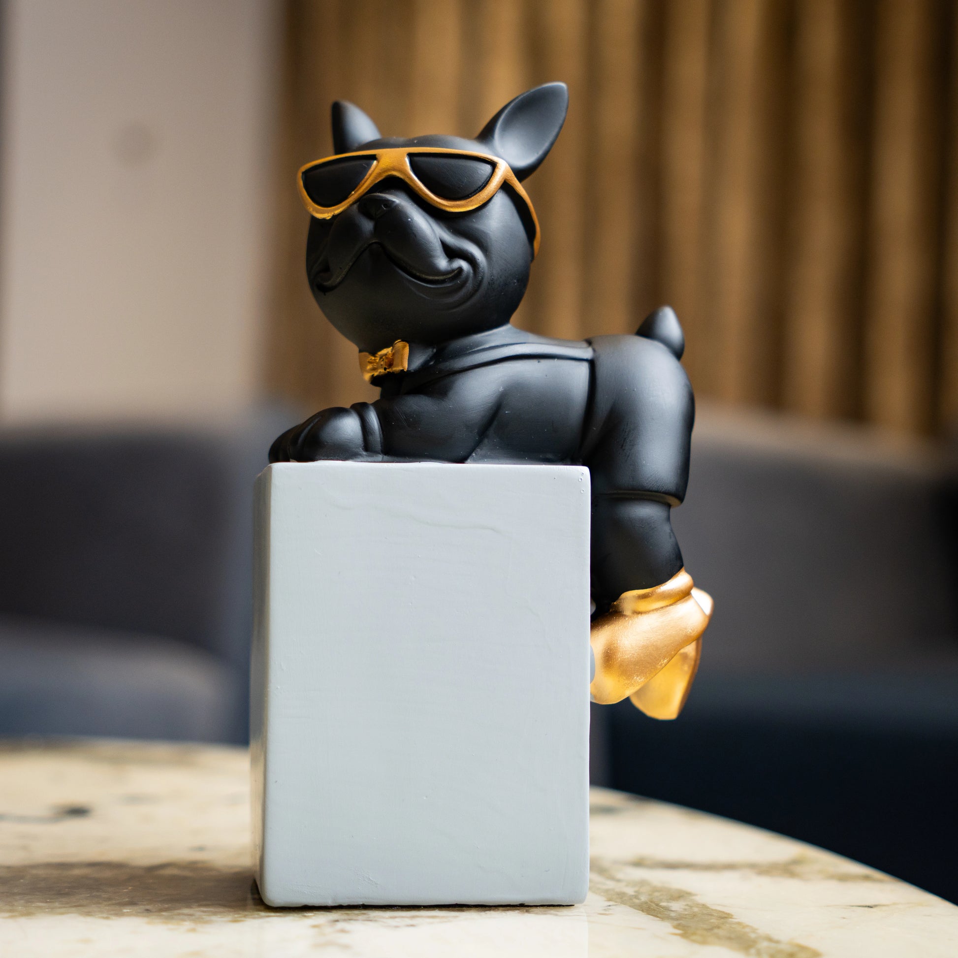 Black resin bulldog figurine trio with gold accents displayed on modern pedestal blocks