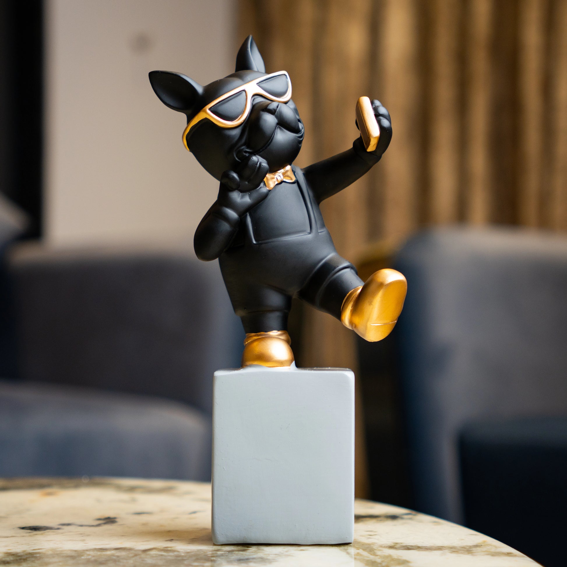 Black resin bulldog figurine trio with gold accents displayed on modern pedestal blocks