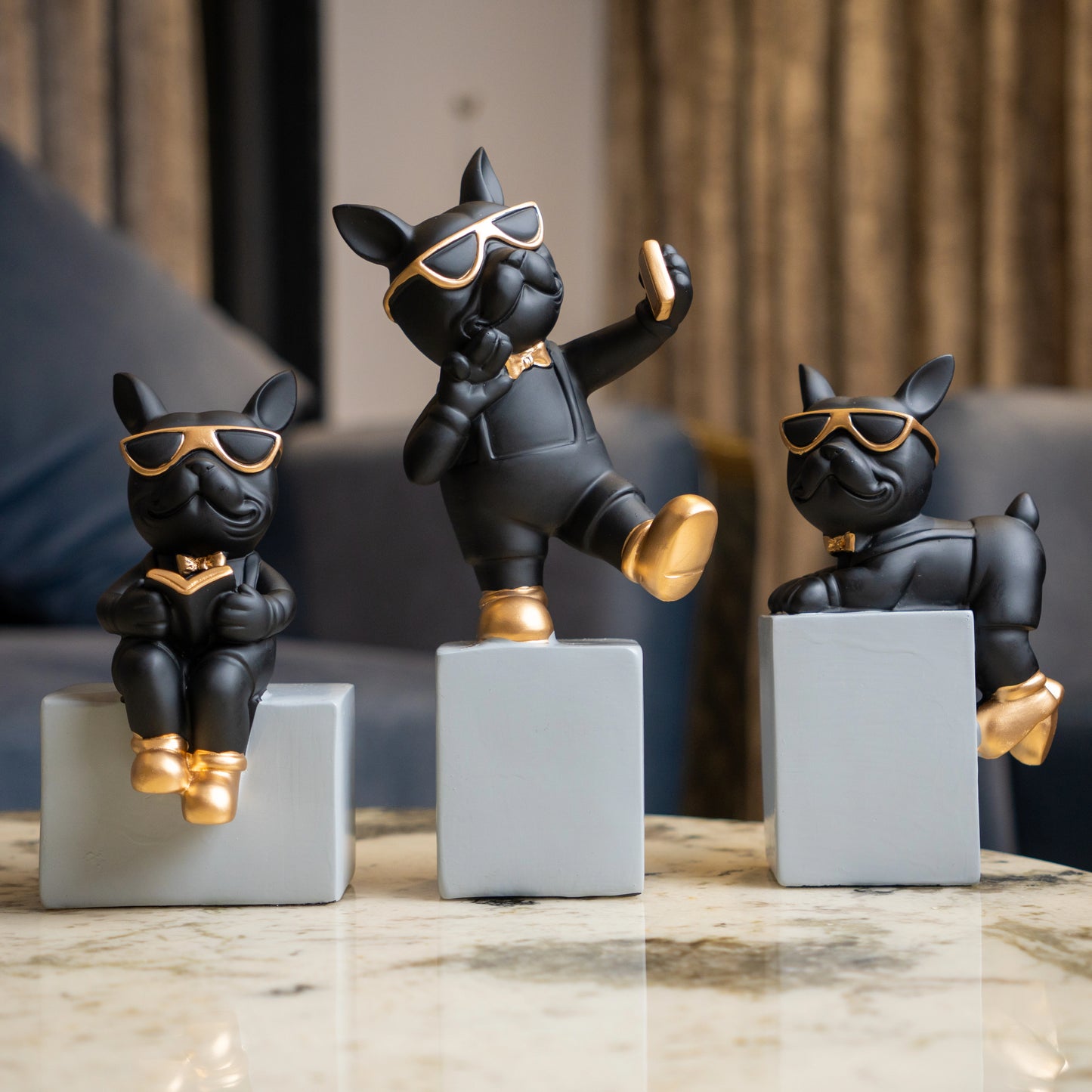 Black resin bulldog figurine trio with gold accents displayed on modern pedestal blocks