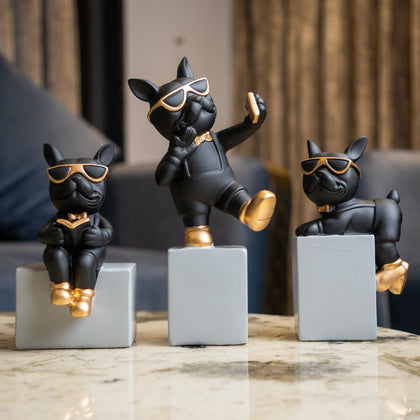Set of three modern black pop art dog figurines with sunglasses and gold accents on geometric bases, cartoon style tabletop decor for living room or office