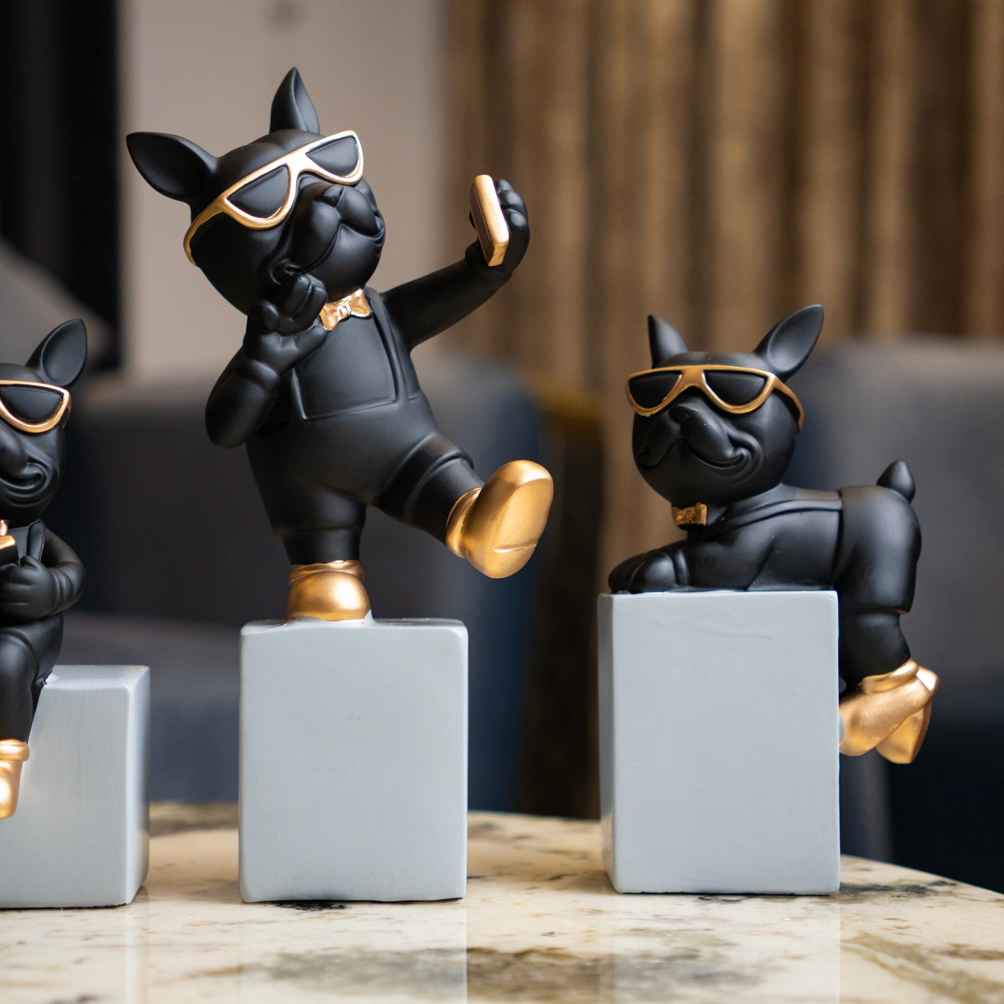 Black resin bulldog figurine trio with gold accents displayed on modern pedestal blocks
