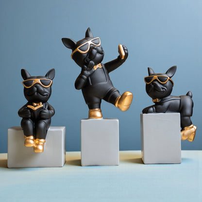 Black resin bulldog figurine trio with gold accents displayed on modern pedestal blocks