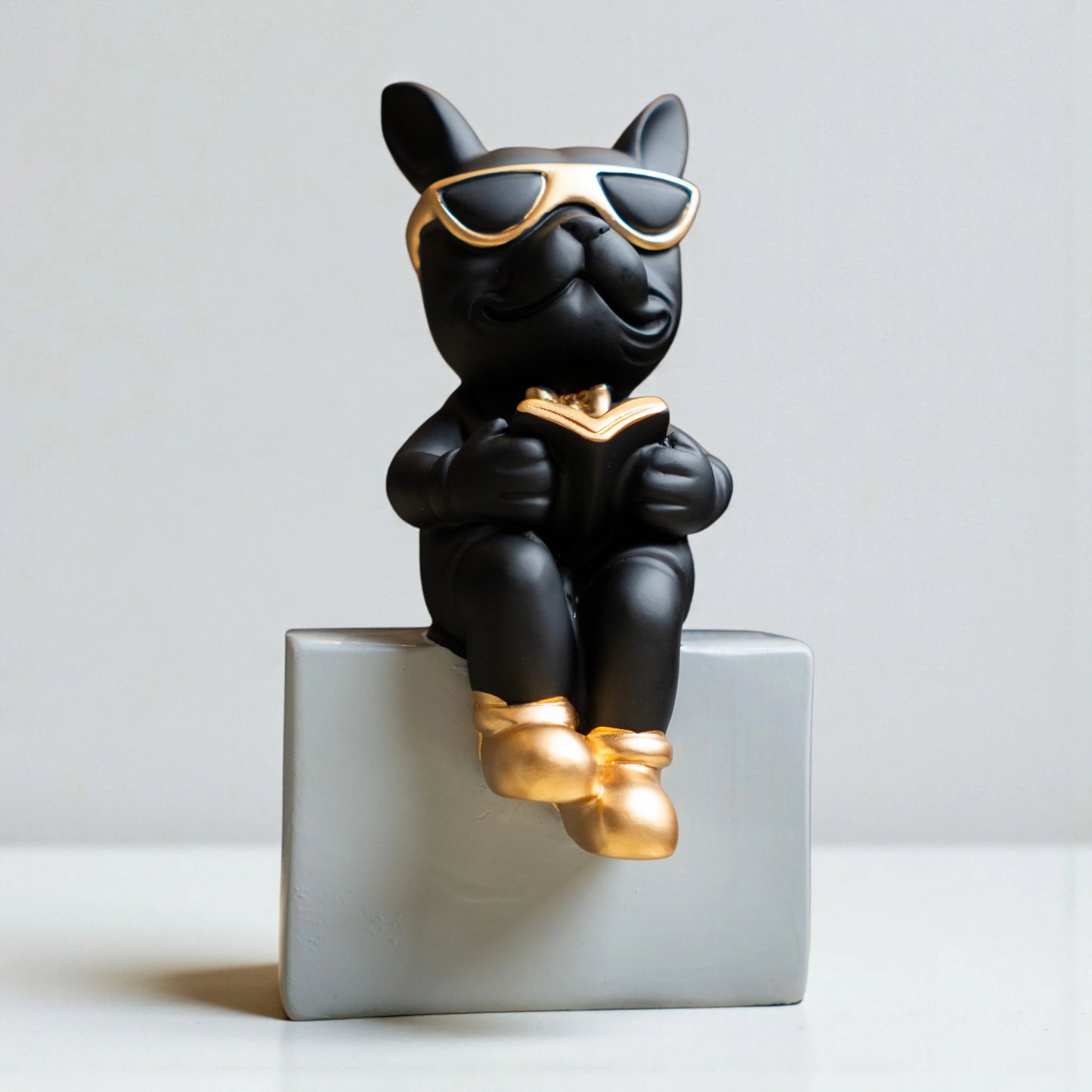 Black resin bulldog figurine trio with gold accents displayed on modern pedestal blocks
