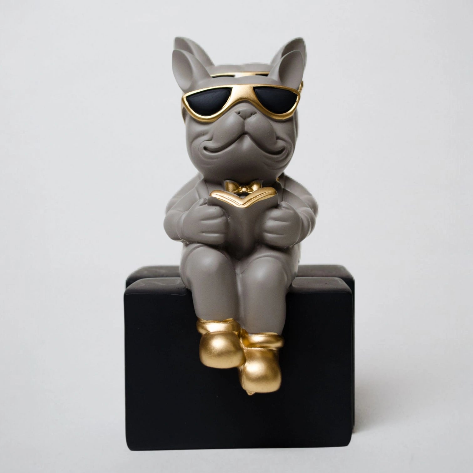 Grey resin bulldog figurine trio with gold accents displayed on black pedestal blocks