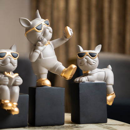 Grey resin bulldog figurine trio with gold accents displayed on black pedestal blocks