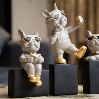 Grey resin bulldog figurine trio with gold accents displayed on black pedestal blocks