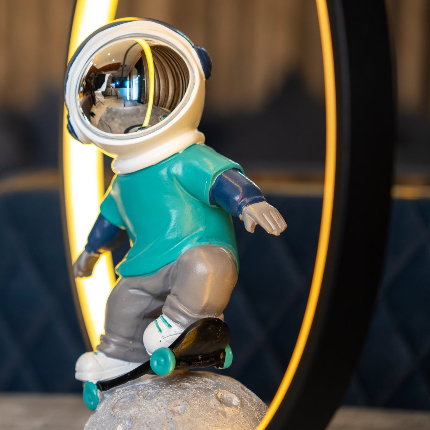 Astronaut skater lamp with teal suit, silver visor and LED ring on moon base