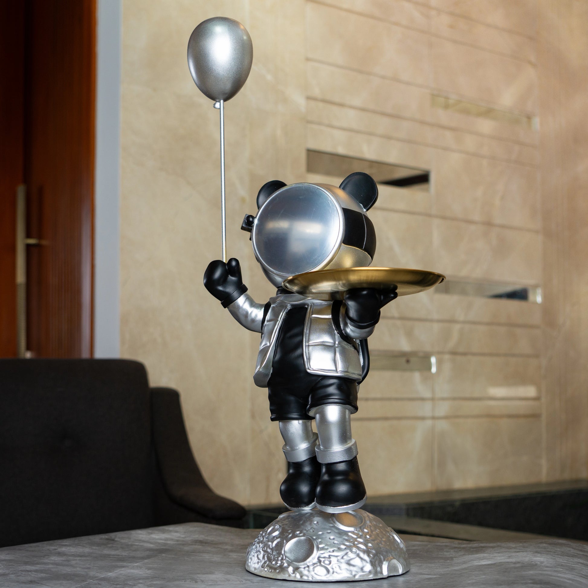 Astronaut bear figurine in silver and black holding a metallic balloon and a gold tray while standing on a moon-textured base; modern resin décor showpiece