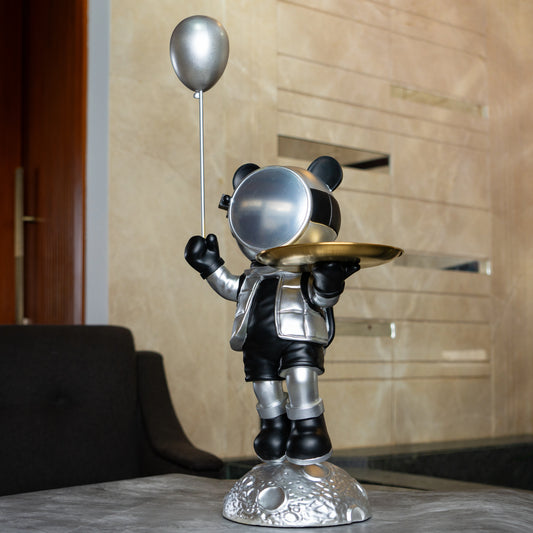 Astronaut bear figurine in silver and black holding a metallic balloon and a gold tray while standing on a moon-textured base; modern resin décor showpiece