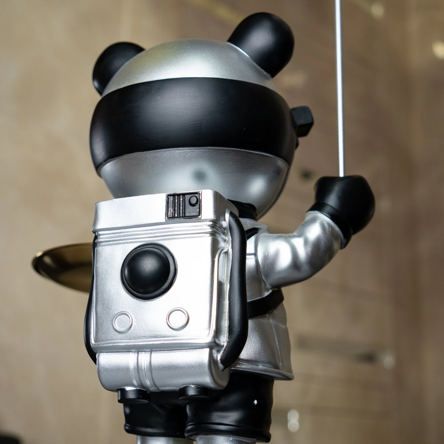 Astronaut bear figurine in silver and black holding a metallic balloon and a gold tray while standing on a moon-textured base; modern resin décor showpiece
