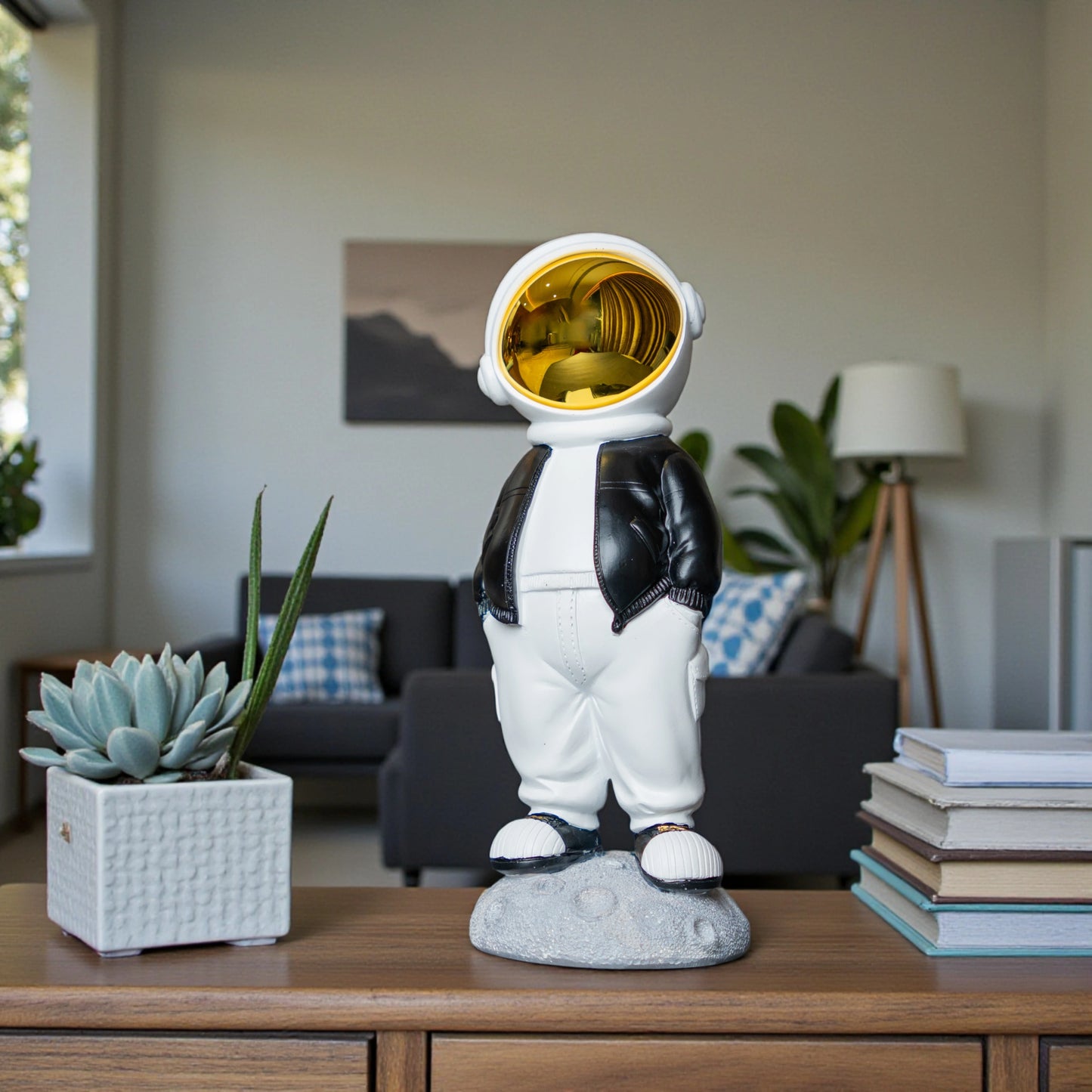 Astronaut figurine with gold visor, black jacket, white pants, and hands-in-pockets pose standing on a moon-textured base; modern resin décor showpiece
