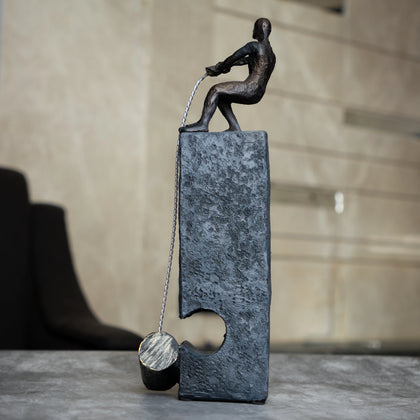 Bronze pulling figure sculpture on textured charcoal