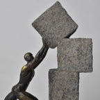 Vertical bronze human sculpture pulling sphere on stepped textured base