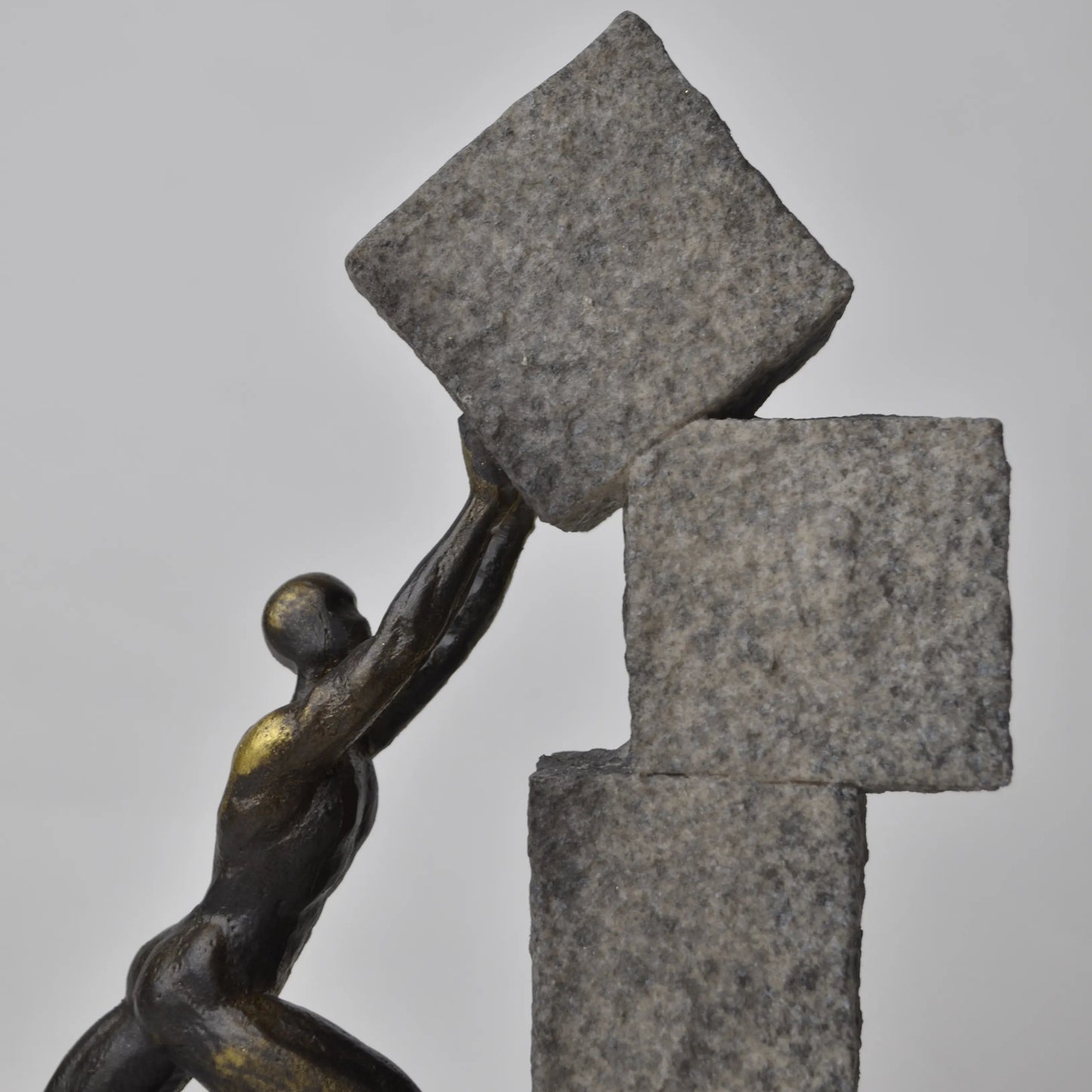 Vertical bronze human sculpture pulling sphere on stepped textured base