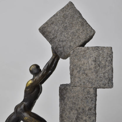 Vertical bronze human sculpture pulling sphere on stepped textured base