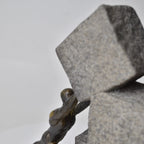 Vertical bronze human sculpture pulling sphere on stepped textured base