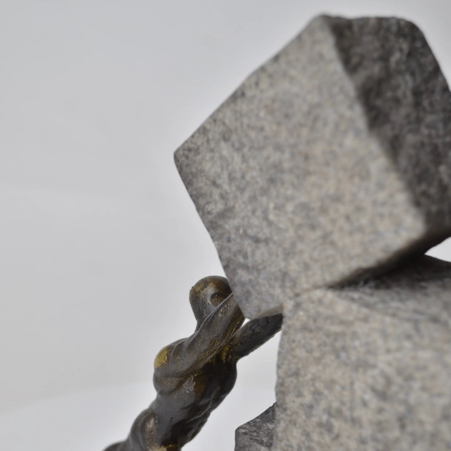 Vertical bronze human sculpture pulling sphere on stepped textured base