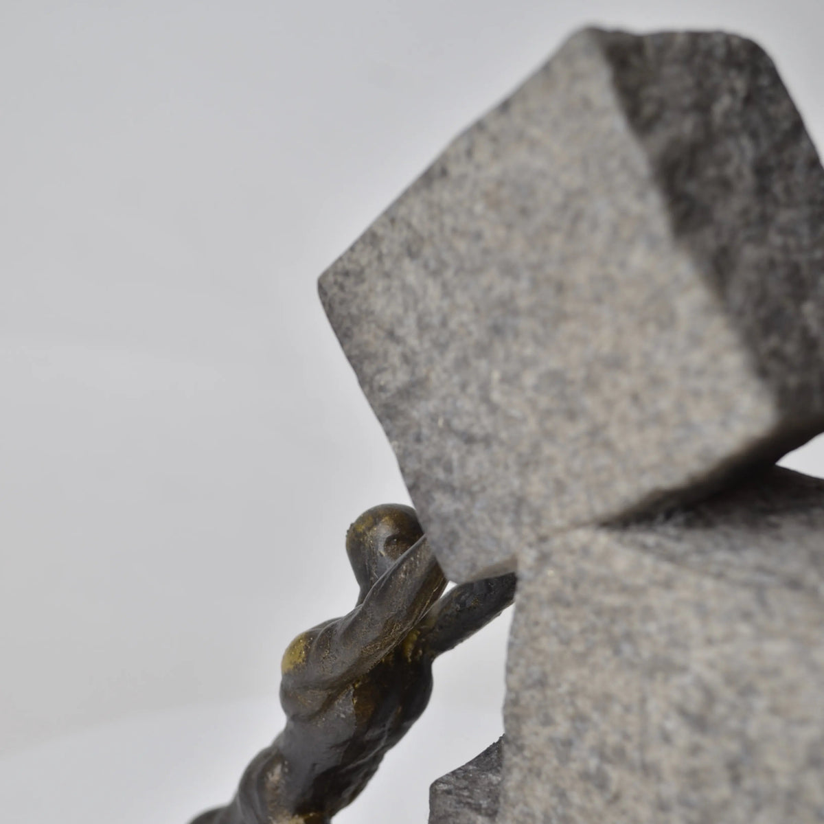 Vertical bronze human sculpture pulling sphere on stepped textured base