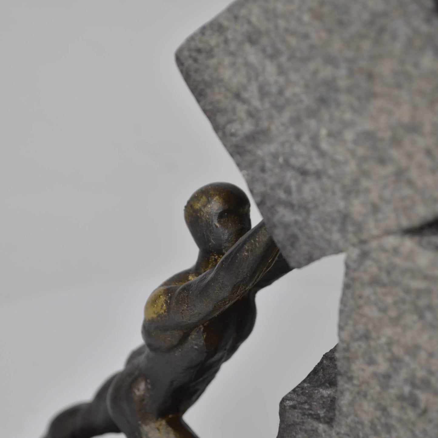 Vertical bronze human sculpture pulling sphere on stepped textured base