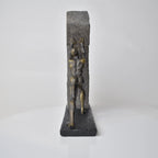 Vertical bronze human sculpture pulling sphere on stepped textured base