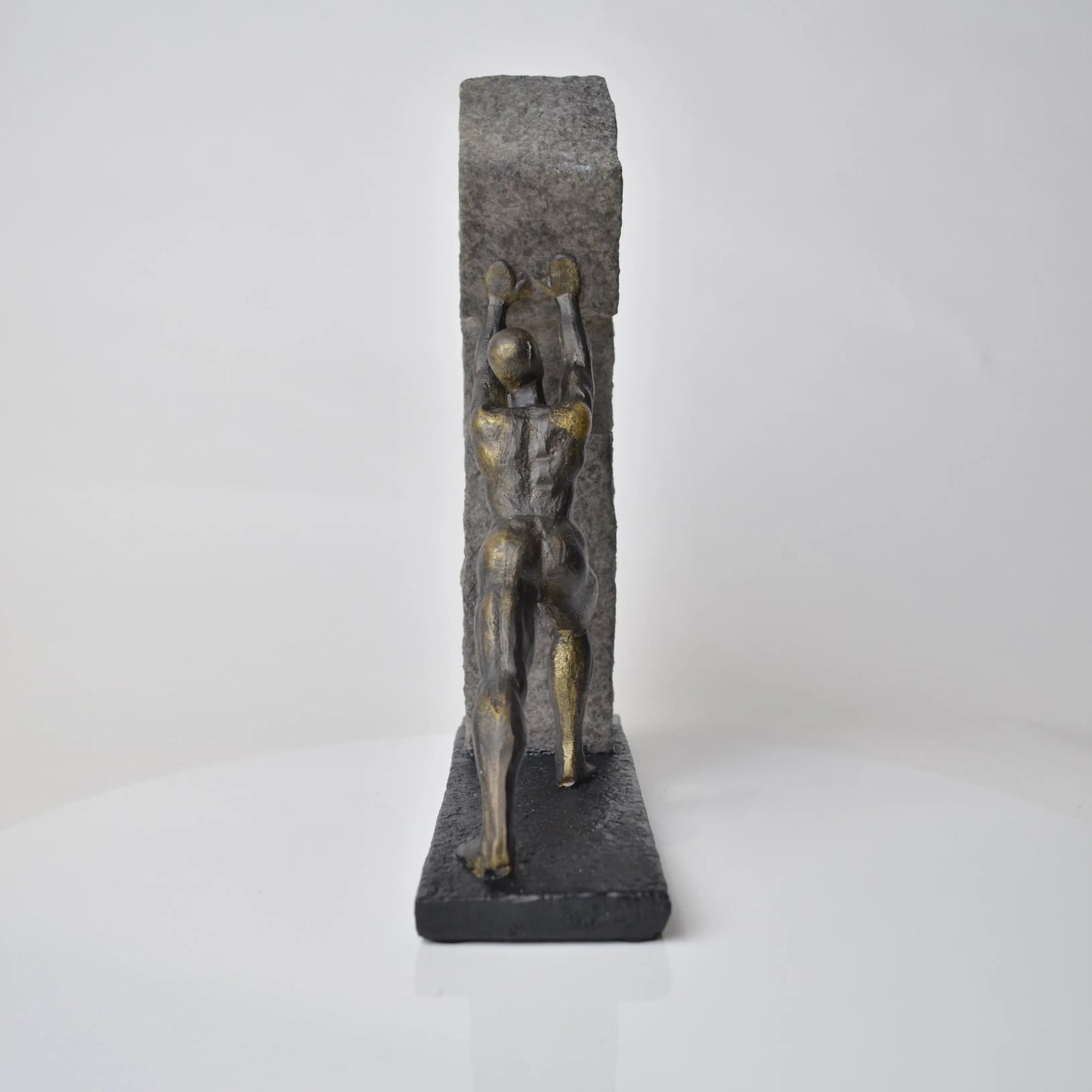 Vertical bronze human sculpture pulling sphere on stepped textured base