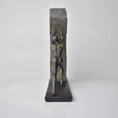 Vertical bronze human sculpture pulling sphere on stepped textured base