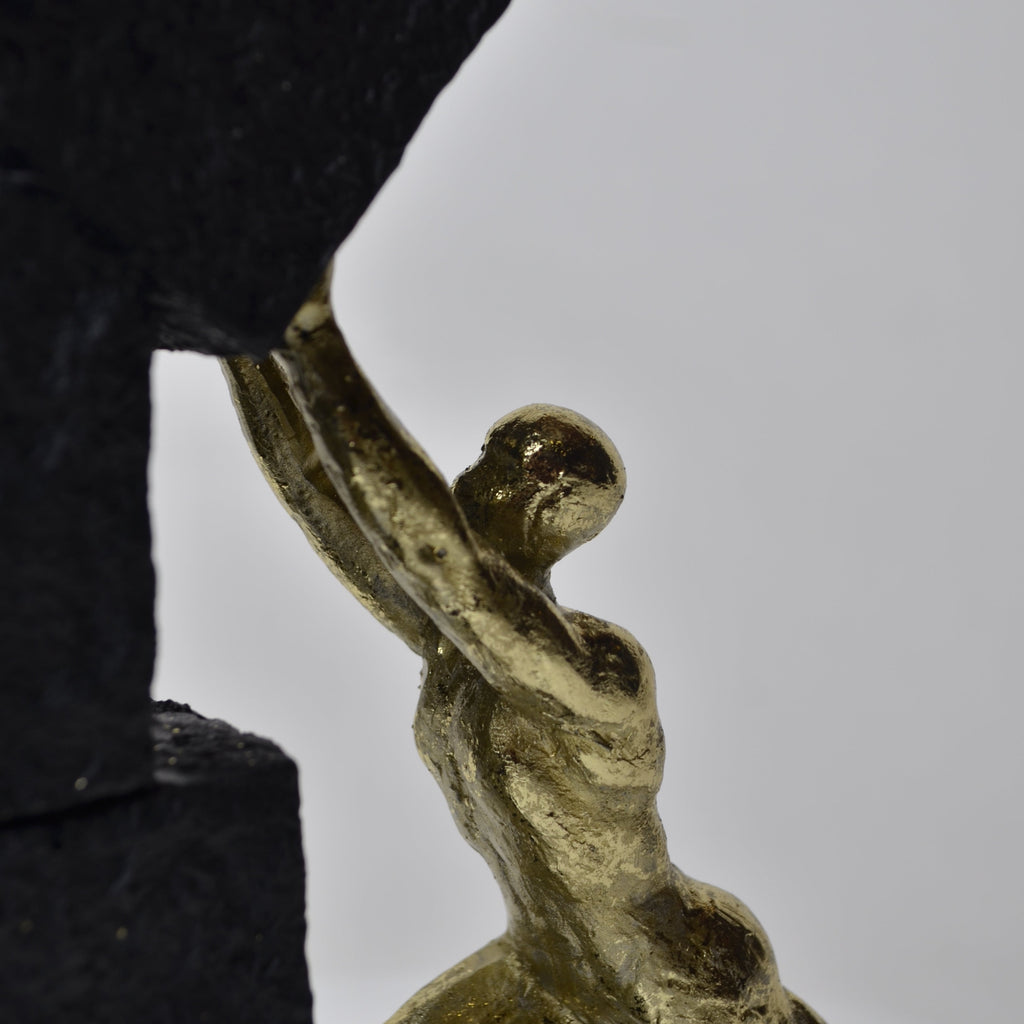 Vertical gold human struggle sculpture pulling textured sphere on stepped base